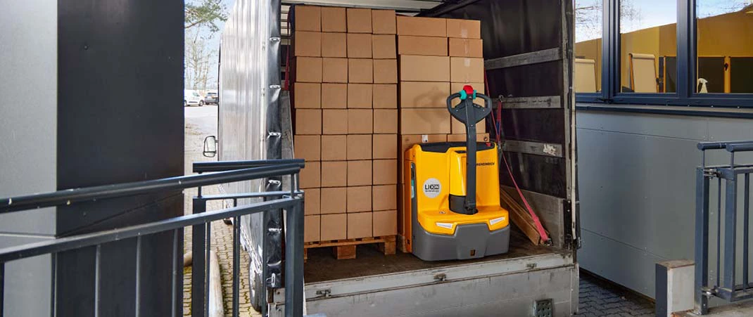 Hubwagen transportieren Ware auf einer Palette in einem Lkw an einer Laderampe