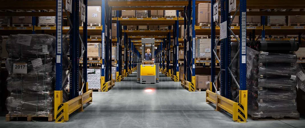 Hochhubwagen fährt durch einen breiten Arbeitsgang im Lager
