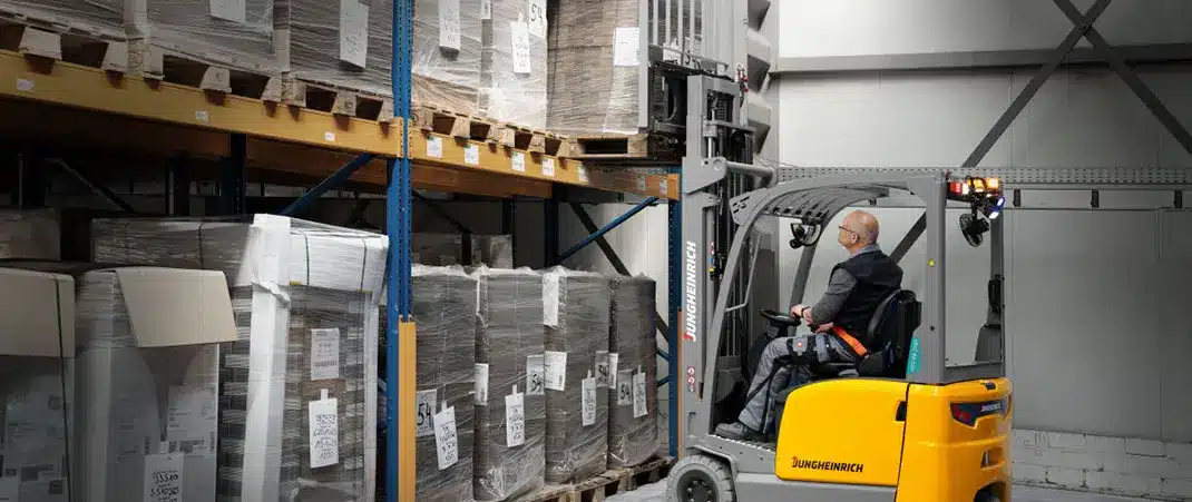 Hubgerüst Gabelstapler: Gabelstapler hebt Palette mit Ware im Hochregallager an